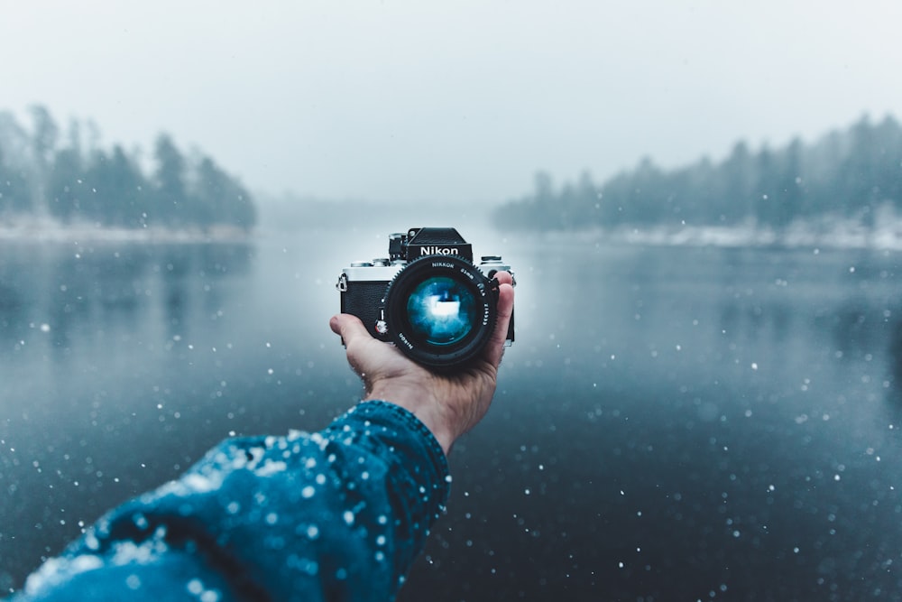 person taking selfie using Nikon DSLR camera