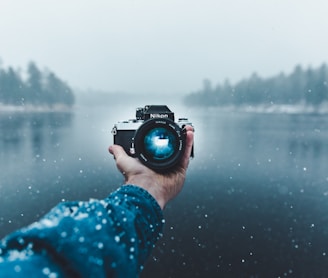 person taking selfie using Nikon DSLR camera