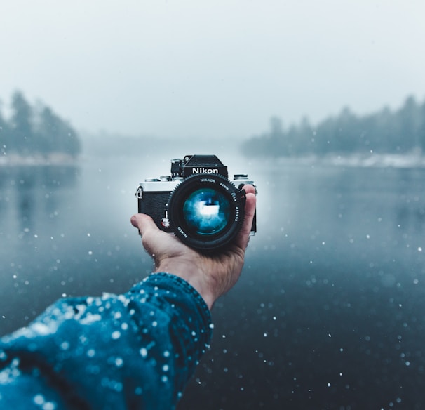 person taking selfie using Nikon DSLR camera