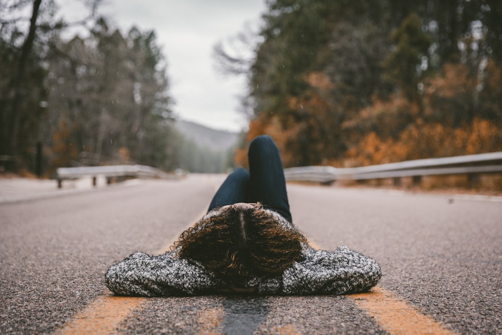 person lying on gray concrete road