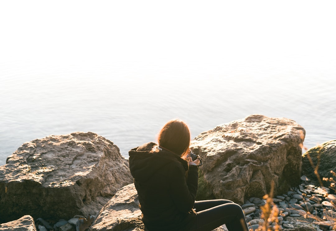 woman wearing black long-sleeved shirt sitting on rock