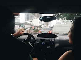 A private driver pointing out a cultural site to happy tourists inside the car.