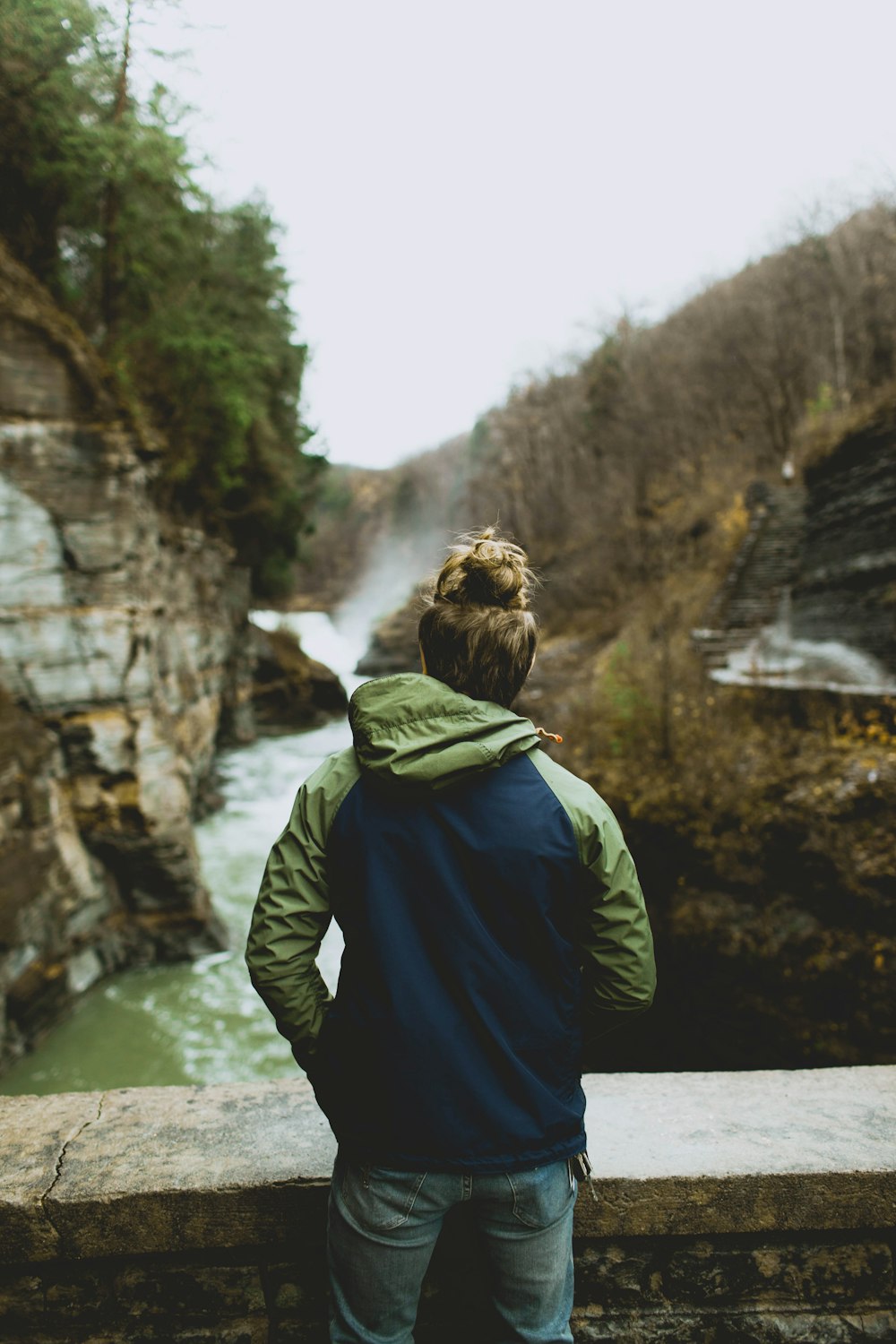 man standing on bridge over river