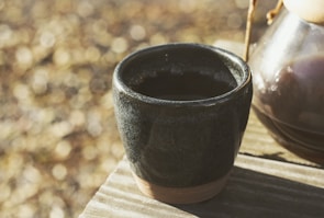 Close-up of a delicate ceramic cup resting on a wooden table with natural light.
