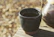 A close-up of a handmade ceramic cup with vibrant glaze, resting on a wooden table bathed in soft morning light.