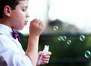 selective photography of boy playing with bubbles