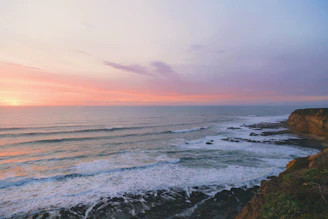 Scenic coastal view of Ventura with waves gently hitting the shoreline at sunset.