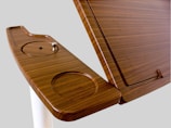 A wooden lecture podium featuring a smooth, polished surface with integrated circular cutouts and a sleek design.