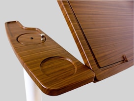 A wooden lecture podium featuring a smooth, polished surface with integrated circular cutouts and a sleek design.