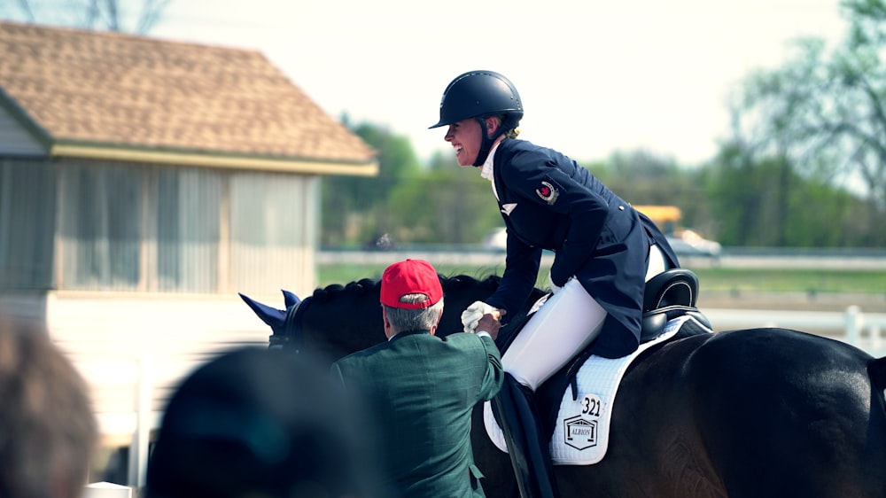 Mann reitet auf Pferd neben Mann, der in der Nähe des Hauses steht