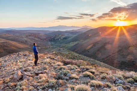 A serene outdoor scene with a person standing on a hilltop at sunrise, symbolizing new perspectives.
