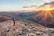A serene landscape with a person standing on a hill, looking towards a sunrise, symbolizing hope and new beginnings.