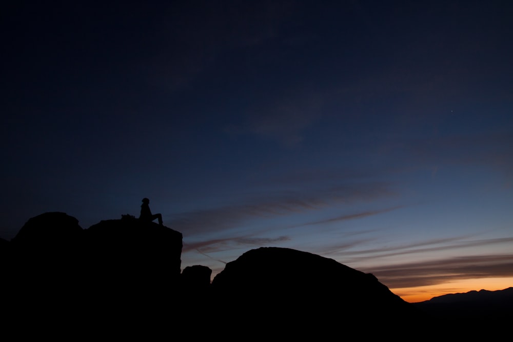 silhouette de personne assise pendant le coucher du soleil