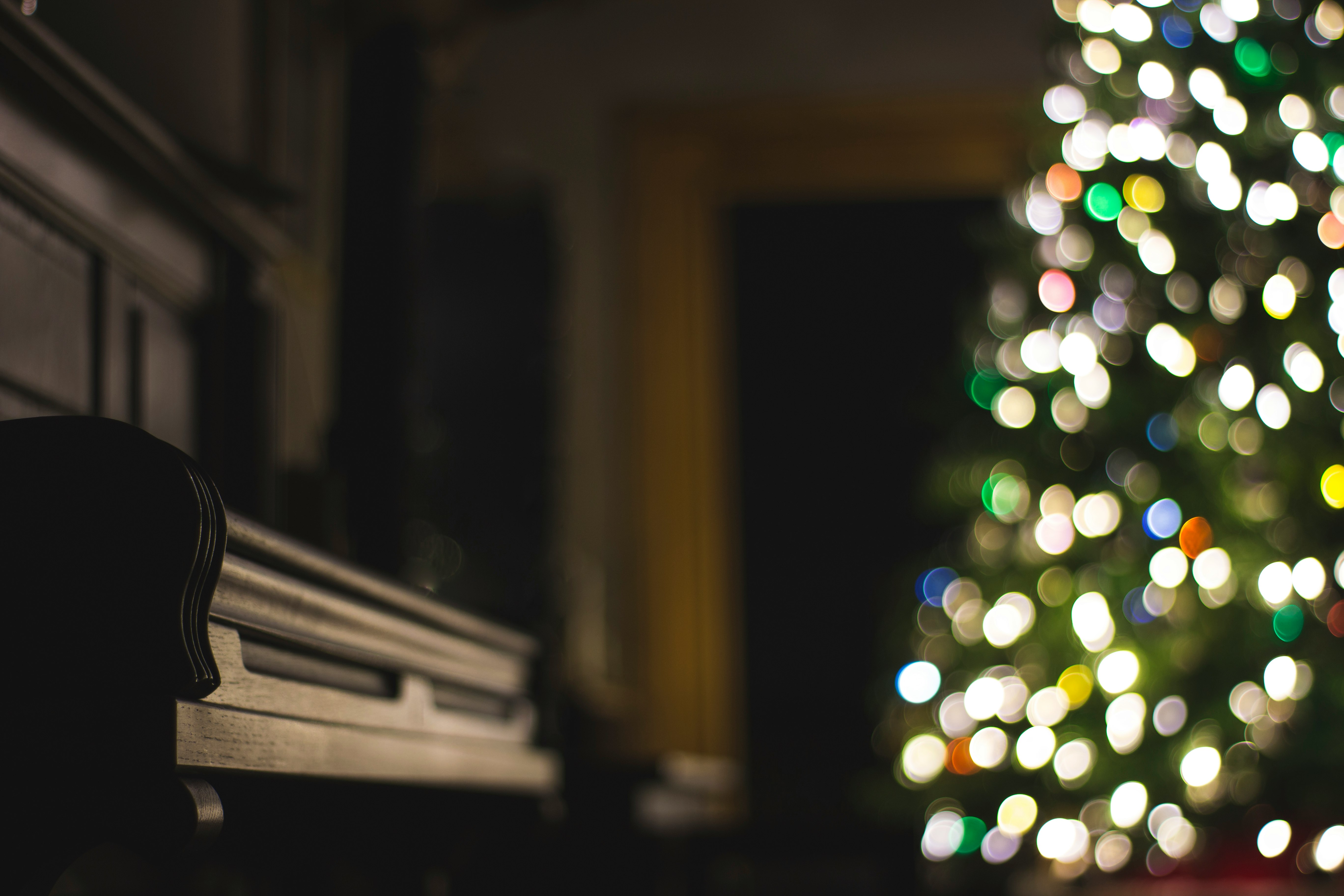 closeup photo of black piano near lighted Christmas tree