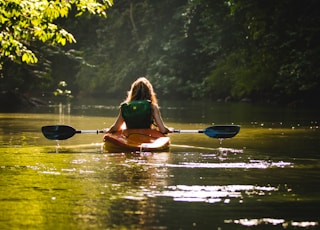 woman on kayak on body of water holding paddle