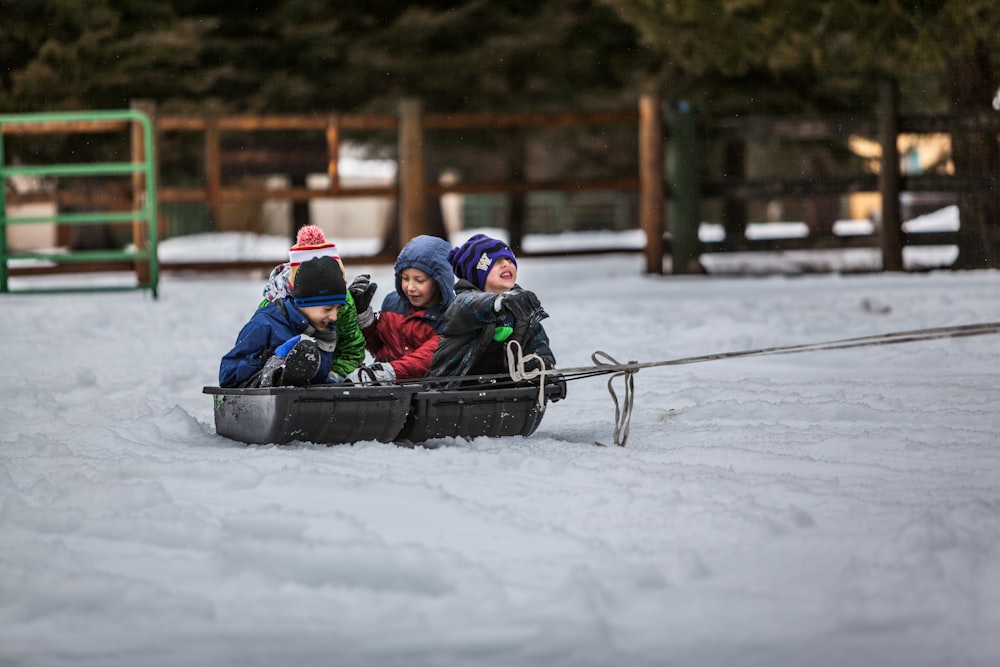 quatro crianças andando de barco na neve