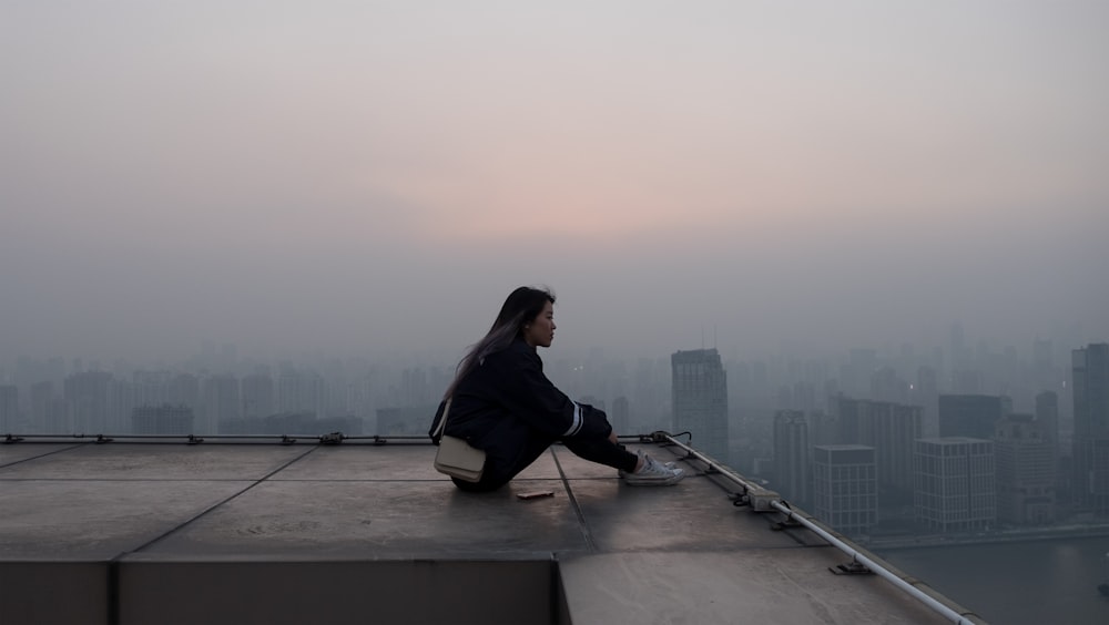 Frau sitzt auf Wolkenkratzer