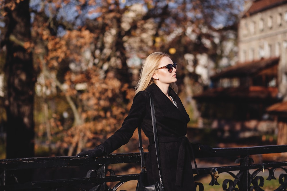 woman leaning on black fence