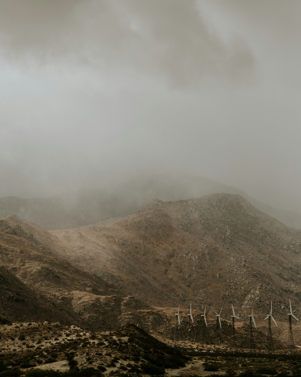 white wind turbines beside mountain