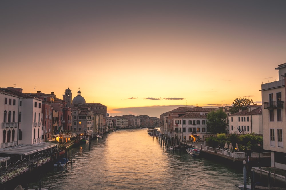 barca sul fiume vicino agli edifici durante il tramonto