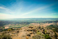 A panoramic view of rolling hills and green valleys under a clear blue sky.