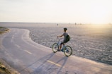 Cyclist riding an e-bike along the sandy beach trail at Riviera de São Lourenço during sunset.