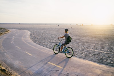 Cyclist riding an e-bike along the sandy beach trail at Riviera de São Lourenço during sunset.