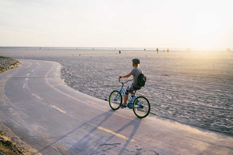 Cyclist riding an e-bike along the sandy beach path at Riviera de São Lourenço during sunset.