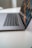 A sleek laptop is partially open on a clean, white surface, with a focus on the keyboard and touchpad. The screen displays a vibrant, digital image with abstract patterns.