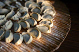 Golden fried dumplings arranged neatly on a rustic wooden board with dipping sauce.