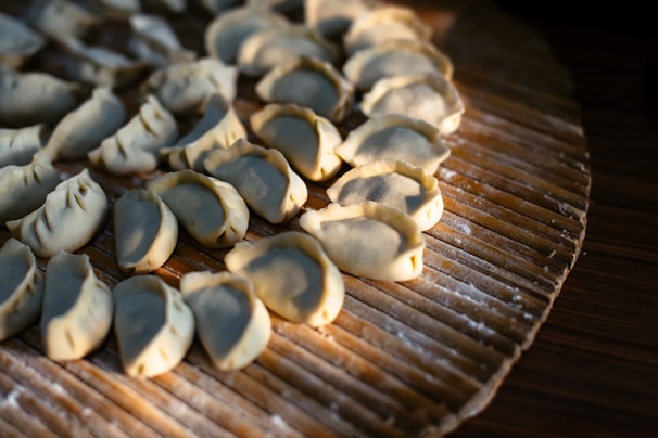 A collection of freshly made dumplings arranged in neat rows on a wooden board dusted with flour.