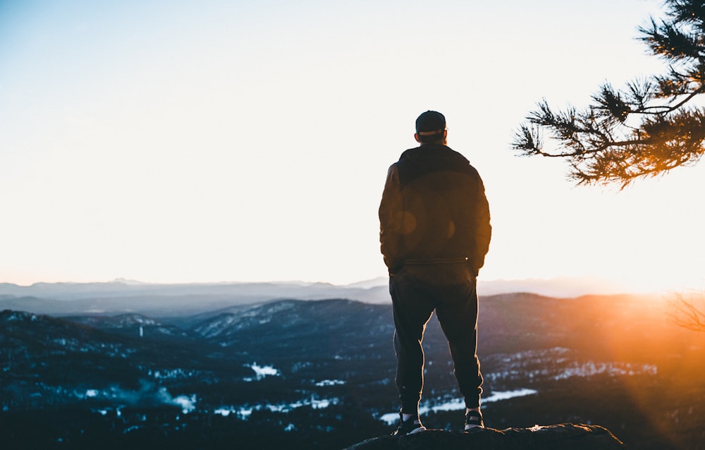 man standing on cliff mountains overview