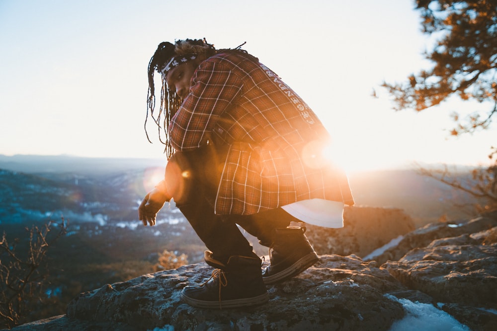 man sitting on rock near cliff