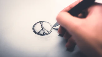 Close-up of hands sketching a bold, minimalist logo on textured paper.