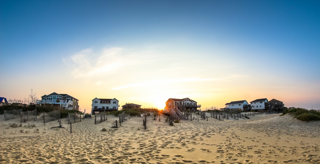 houses on seashore, Sitting on the beach with my family one evening, watching dolphins play, as the sun made its way down behind us. I turned to head back inside, and noticed the gorgeous light streaming just beyond these low sand dunes. So, I grabbed my camera to snap this quick picture.
