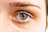 A close-up view of a human eye showcasing intricate details of the iris, eyelashes, and surrounding skin textures. The iris displays a mix of blue and brown colors, creating a striking appearance.