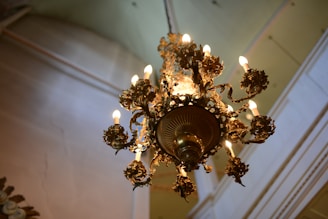 Elegant wrought iron chandelier glowing warmly in a rustic room.
