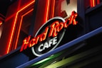 Bright neon lights and a bold logo represent a recognizable cafe brand. The sign is prominently displayed against a dark backdrop, highlighting the vibrant red and white text.