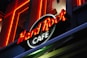Bright neon lights and a bold logo represent a recognizable cafe brand. The sign is prominently displayed against a dark backdrop, highlighting the vibrant red and white text.
