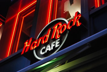 Bright neon lights and a bold logo represent a recognizable cafe brand. The sign is prominently displayed against a dark backdrop, highlighting the vibrant red and white text.