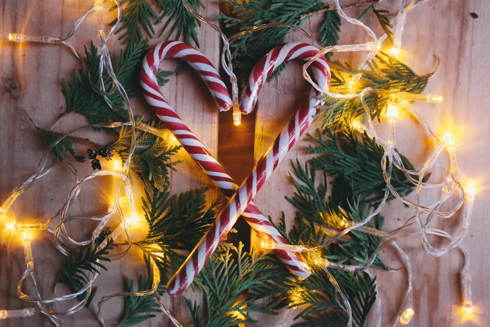 Candy canes sitting inside of a wreath, surrounded by Christmas lights.