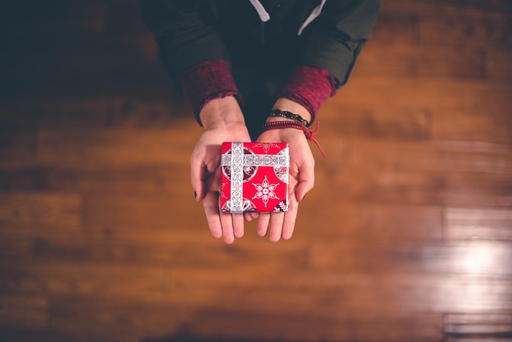 Hands outstretched with a Christmas gift wrapped in holiday wrapping paper