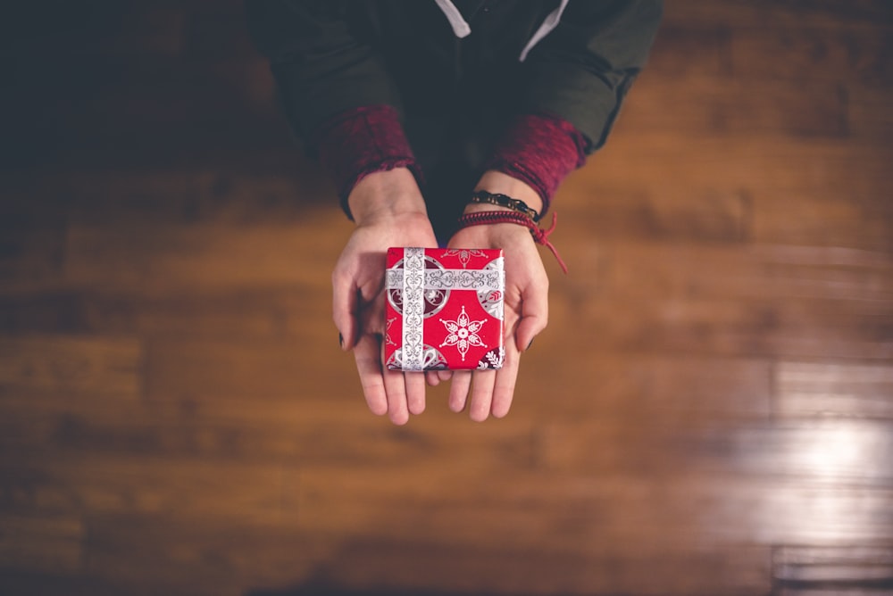 person holding red and white box