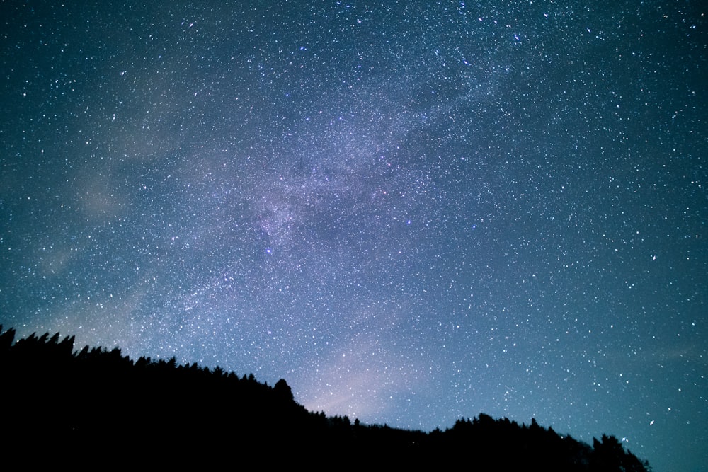 the night sky with stars above a hill