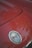 A close-up view of a red car's hood featuring the Chevrolet Corvette emblem, which includes the brand’s iconic crossed flags badge.
