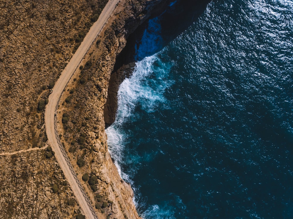 Photographie aérienne d’une falaise brune à côté d’un plan d’eau
