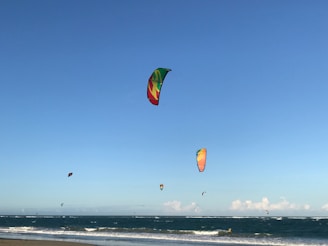 A close-up of colorful kites soaring in the blue sky above the beach.