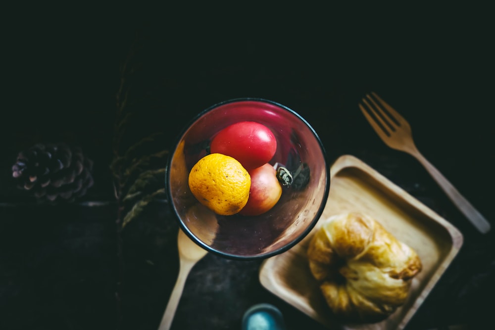 manzana y naranja en un tazón al lado del plato y el tenedor