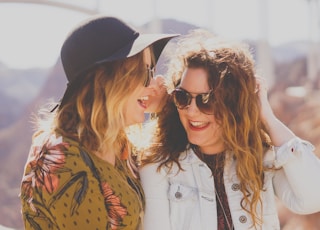 two women smiling while wearing sunglasses