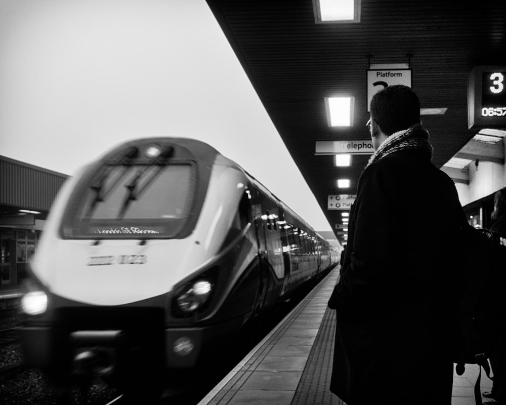 man standing beside moving train